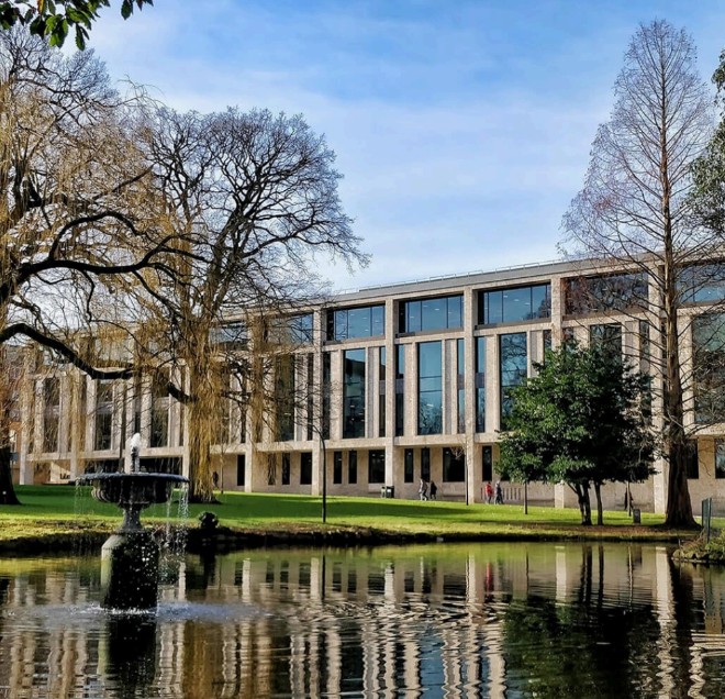 The University of Roehampton campus, with its stone and glass building viewed across the lawn and ornamental fountain pond