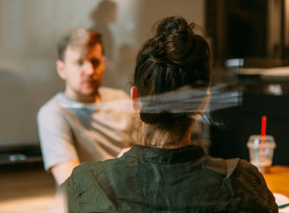 Two people behind window glass talking in a meeting