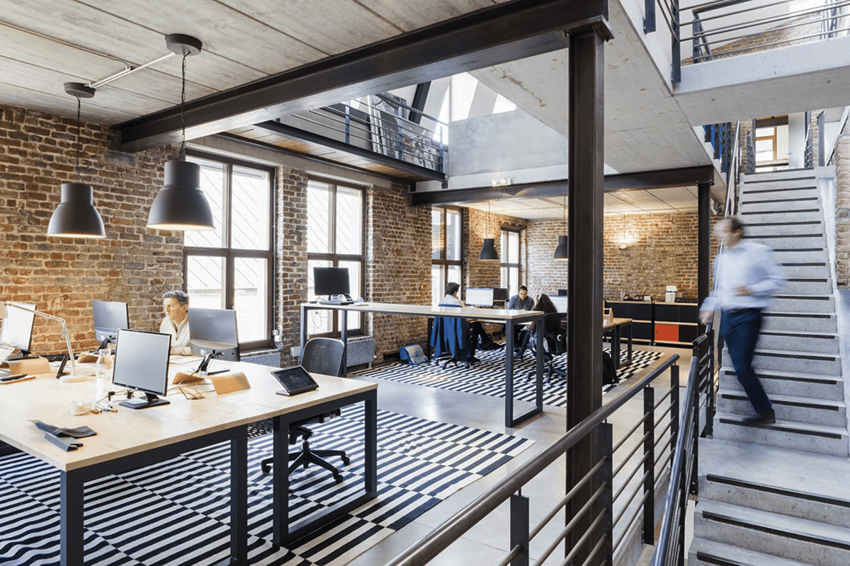 An office with a couple of people in it moving around